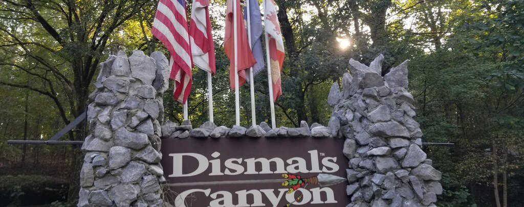 Stone entrance sign surrounded by forest at Dismals Canyon in Alabama