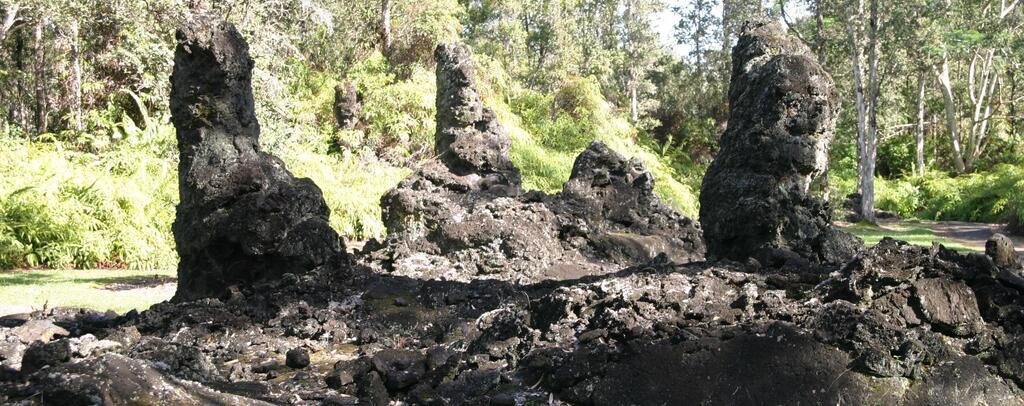 Tall hollow lava molds stand among vegetation at Lava Tree State Monument.
